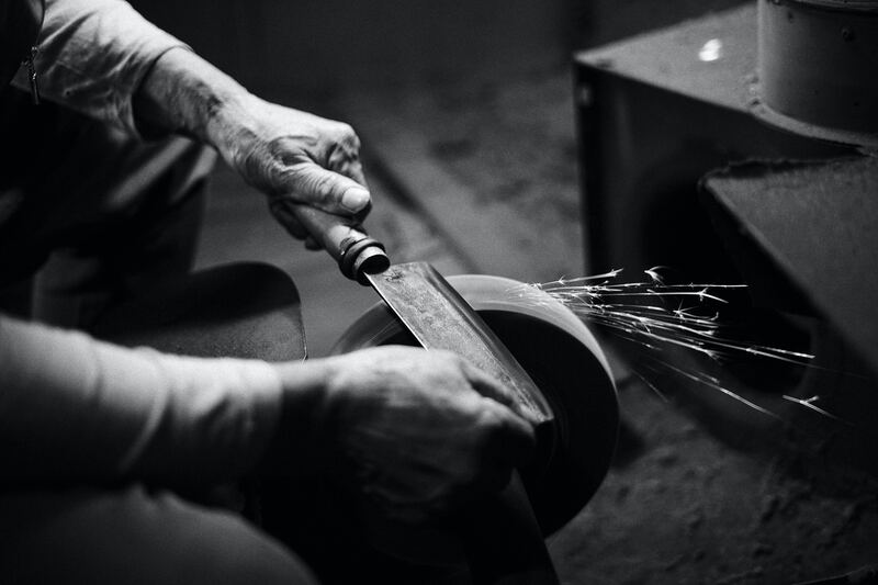 artisan affûtant un couteau sur une roue d'aiguisage